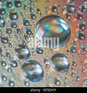 A macro shot of water droplets on the surface of a compact disc. Stock Photo