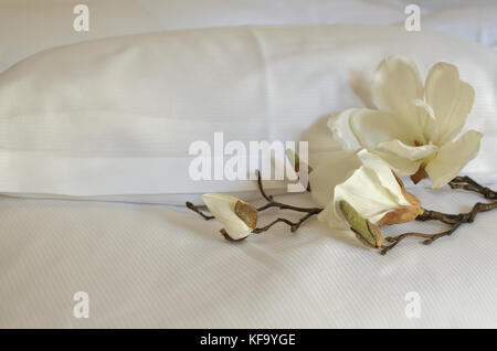 Two pillows in white cases and artificial orchids on them Stock Photo