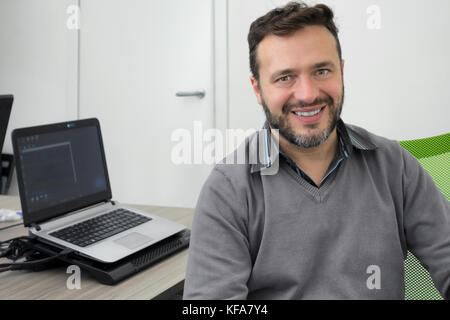 happy young business man, software developer, computer technician working in modern office of a start up Stock Photo