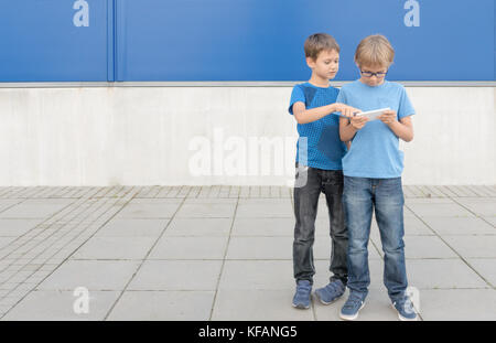 Childen using mobile phone outdoors Stock Photo
