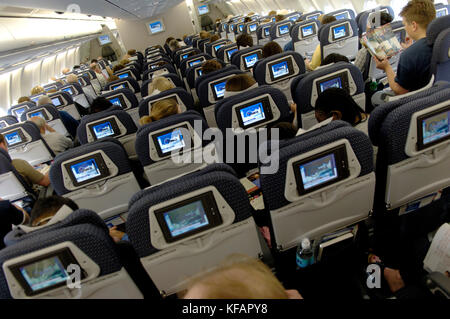 passengers sitting the economy-class cabin of a Northwest Airlines Airbus A330-300 flight-number NW44 enroute MSP-LGW with video screens Stock Photo