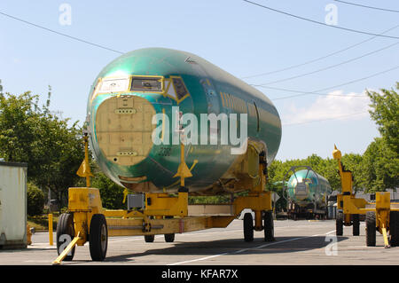 a fuselage section of a Boeing 737-700 (LN2350) on a trolley with another fuselage (LN2353) on a railroad-flatcar behind outside the production factor Stock Photo