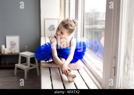 little girl dreams of becoming a ballerina. Child girl in a blue ballet costume dancing in a room. Stock Photo