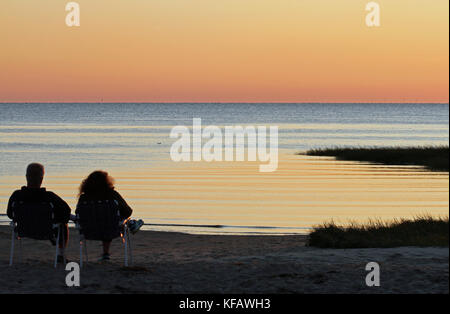 A silhouette of a couple watching a sunset at First Encounter Beach on Cape Cod Bay, Eastham, Massachusetts Stock Photo