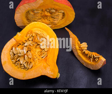 fresh pumpkin with seeds cut in half on a black background, close up Stock Photo
