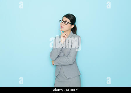 beauty professional banker woman in blue background having job problem and looking at empty area thinking about working solution. Stock Photo