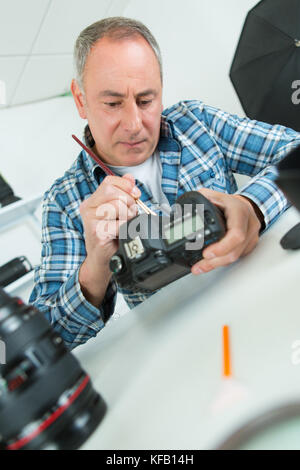 focused middle-age man fixing retro camera at his workplace Stock Photo