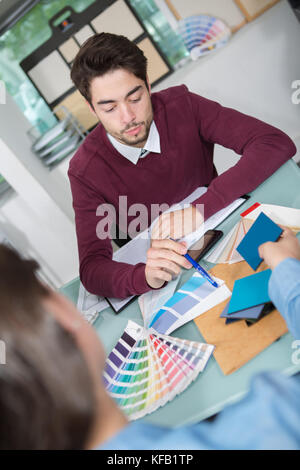 interior designer showing colour wheel to customer in his studio Stock Photo