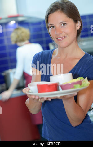 pretty barmaid holding plates of salads in a bar Stock Photo