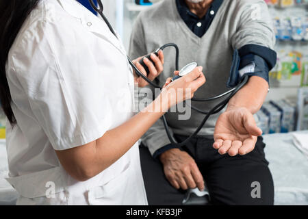 Midsection Of Chemist Checking Patient's Blood Pressure Stock Photo
