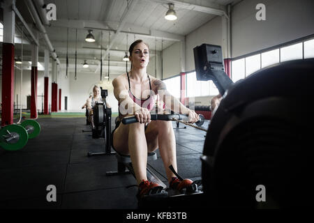 Determined Woman Exercising On Rowing Machine Stock Photo