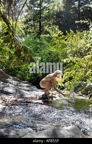 USA, California, Big Sur, Esalen, a woman puts her hand into Hot Springs Creek at the Esalen Institute Stock Photo