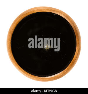Apple juice concentrate in wooden bowl. Dark brown fruit juice. Syrup made of pressed apples and further treated by dehydration. Sugar substitute. Stock Photo