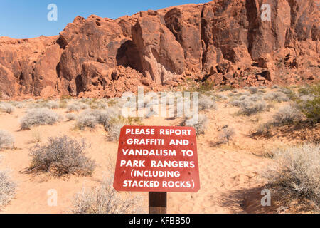 Valley of Fire State Park Nevada,  sign warning to report graffiti and vandalism to park rangers including stacked rocks. Stock Photo