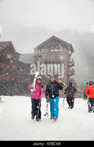 USA, Colorado, Aspen, skiers at the Highlands Mountain base walk in the falling snow, Highlands Ski Resort Stock Photo