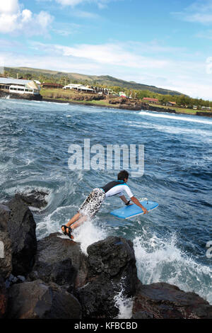 EASTER ISLAND, CHILE, Isla de Pascua, Rapa Nui, a young boy jumps into the water on his boogie board in Hanga Roa Stock Photo