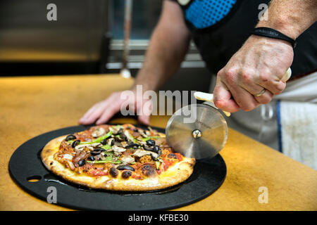 USA, Oregon, Bend, Pacific Pizza and Brew, slicing mini pizza Stock Photo