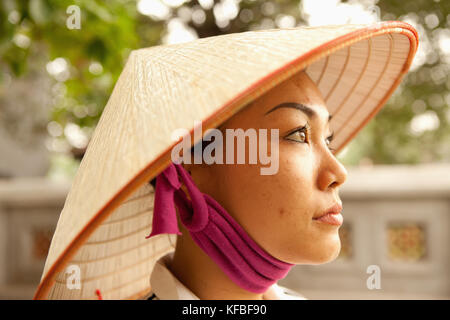 VIETNAM, Hanoi, portrait of a young woman wearing a non la or leaf hat, Hoan Kiem Lake Stock Photo