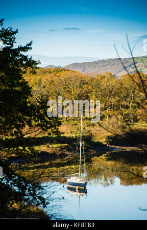 Powys, Wales UK Friday 27 October 2017 UK Weather: A yacht is moored in the mirror-calm water, reflecting the bbeautiful autumn colours on a bright sunny, but cold, morning on the Dyfi Estuary, near Machynlleth, Powys, Wales photo Credit: Keith Morris/Alamy Live News Stock Photo