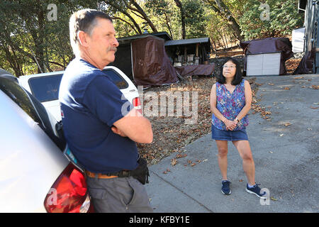 Napa, CA, USA. 25th Oct, 2017. Lisa Hirayama, right, listens as her husband Larry Carr, a battalion chief with the El Cerrito Fire Department, describes his actions during the recent Atlas Fire in their Circle Oaks neighborhood. When wildfires threatened homes in his rural neighborhood, he stayed on the scene for about eight days, helping to battle the fire and helping to deploy firefighters in the area. Credit: Napa Valley Register/ZUMA Wire/Alamy Live News Stock Photo