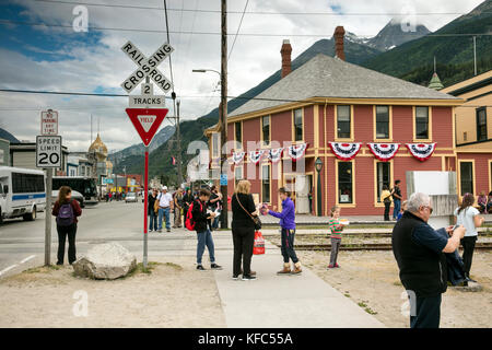 USA Alaska, Sitka, individuals walking the streets of downtown Sitka wait for the train traveling on the White Pass & Yukon Route Railroad to pass Stock Photo