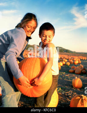 USA, California, girl and boy carrying a pumpkin at Bob's Pumpkin Patch, Half Moon Bay Stock Photo