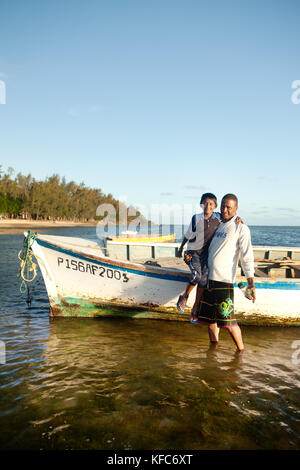 MAURITIUS, father and son stand in front of a fishing boat after a long day on the water, Bel Ombre, Indian Ocean Stock Photo