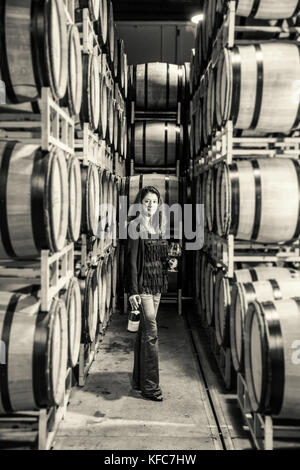 USA, Oregon, Willamette Valley, Dyane Savino stands amidst barrels of wine in the barrel room at Domaine Drouhin, Dundee Stock Photo