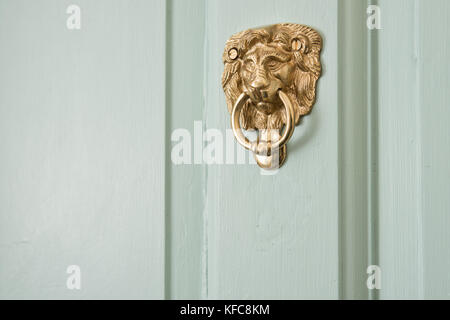 An ornate, brass, lions head door knocker. Mounted to the front door of a UK home. Stock Photo