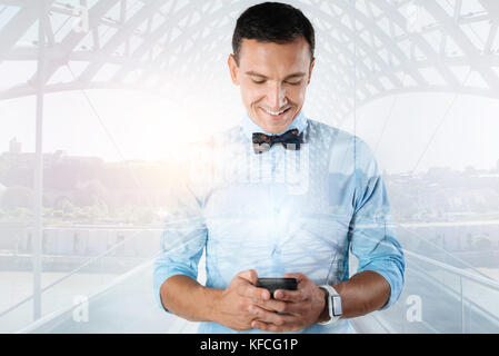 Cheerful delighted man using his smartphone Stock Photo