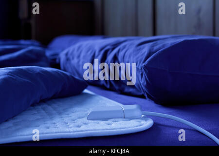 Electric heating blanket on a bed at night, thermotherapy for fibromyalgia syndrome and other rheumatic diseases Stock Photo
