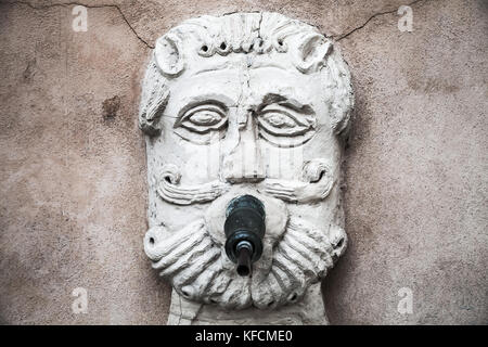 Ancient fountain with drinking water in the shape of a bearded male face. Fermo, Italy Stock Photo