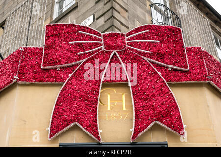 Giant Christmas bow on shop front of Chisholm Hunter jewellers, corner of Frederick Street and Princes Street, Edinburgh city centre, Scotland, UK Stock Photo
