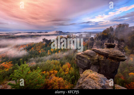 Foggy sunrise in the Saxon Switzerland, Germany, view from the Bastei lookout point. The Bastei is a tourist attraction for over 200 years. Stock Photo