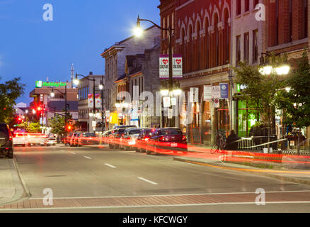 Cars driving by historical buildings along Princess Street at dusk in downtown Kingston, Ontario, Canada. Stock Photo