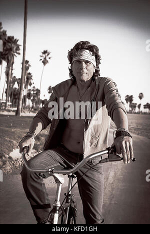 USA, Los Angeles, a man riding his bike down the Venice Boardwalk Stock Photo