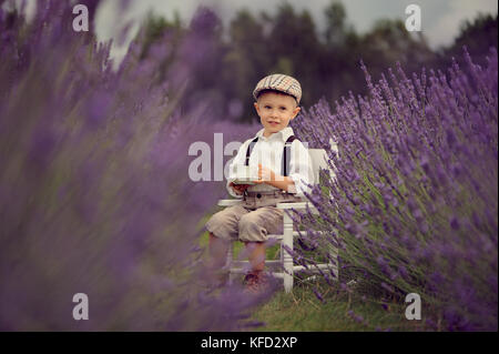 A small four year-old smiling boy  on a lavender field at sunny summer day Stock Photo