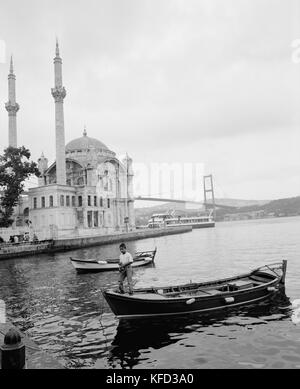 TURKEY, Istanbul, boy standing on boat with Ortakoy Mosque in the background Stock Photo