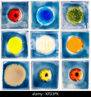 Collection of blue handmade glazed ceramic tiles with other color dots in middle isolated on white background. Colorful pottery craft items. Stock Photo
