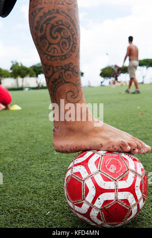 FRENCH POLYNESIA, Tahiti, Papeete. A soccer game between locals at the Willy Bambridge Stadium. A young soccer player playing with the ball. Stock Photo