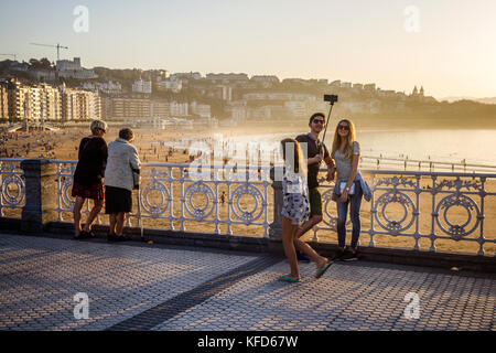 Young couple take selfie on promenade, Concha beach, San Sebastian, Basque Country, Spain. Stock Photo