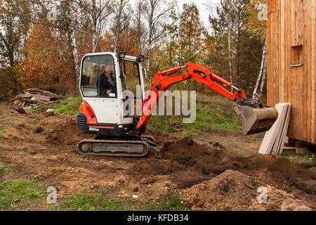 Mini excavator on construction site. Excavator regulates the terrain around the house. Stock Photo