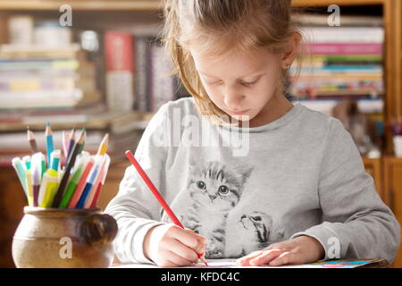 Girl coloring on paper having creative time at home Stock Photo