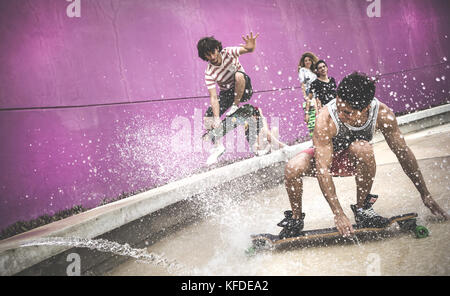 A skateboarder crouching down to skate through water. Stock Photo