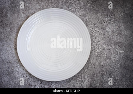 Empty white ceramic plate On a concrete background. Top view with copy space Stock Photo