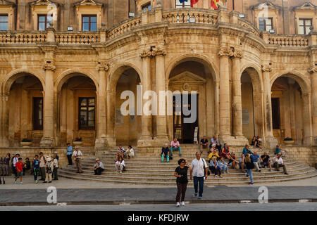 TNoto, Sicily, Italy – September 27, 2017: Tourists sitting on the steps of a ladder of the Palazzo Ducezio – Noto Town Hall Stock Photo