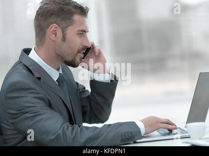 closeup.businessman working on laptop and talking on the phone. photo with copy space Stock Photo