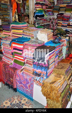 Stacks of colorful handmade pure wool rugs in tourist stall of Old Bazaar of Antalya, Turkey