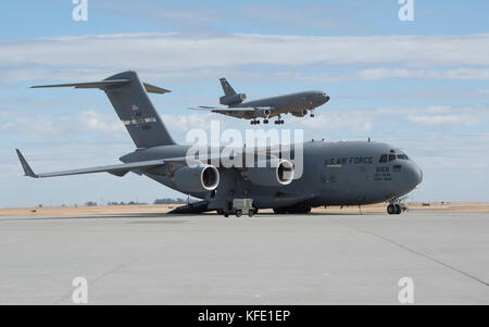 KC-10 Extender makes its final approach as a C-17 Globemaster III parked on the ramp is serviced, Oct. 19, 2017 Stock Photo