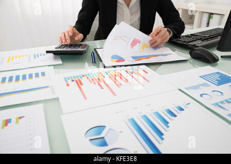 Businesswoman Analyzing Report On Chart With Calculator Stock Photo